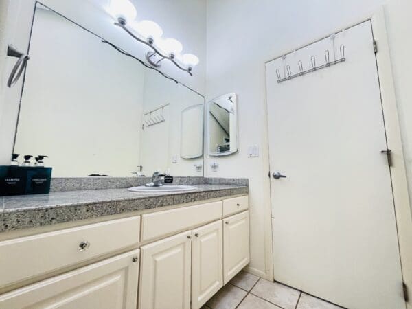 A bathroom with white cabinets and a mirror.