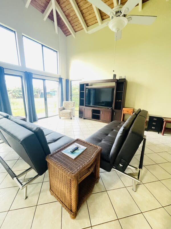 A living room with two black leather chairs and a television.