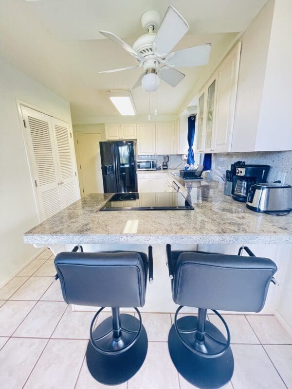 A kitchen with two black stools and a counter