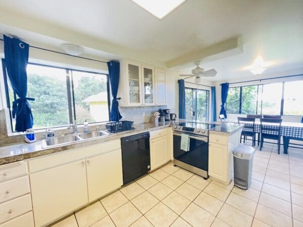 A kitchen with white cabinets and blue curtains.