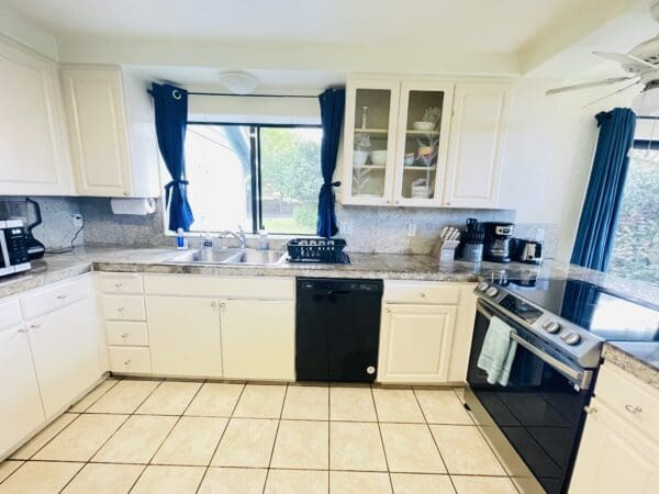 A kitchen with white cabinets and black appliances.