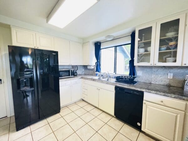 A kitchen with white cabinets and black appliances.