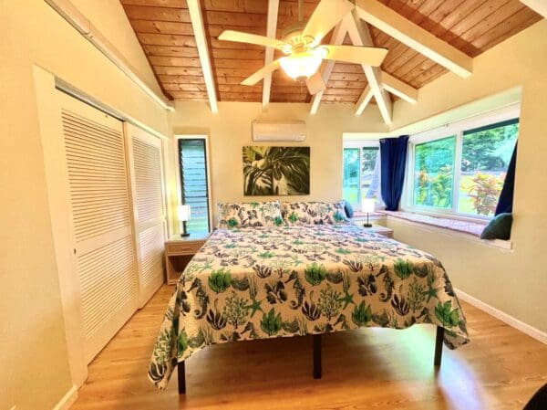 A bedroom with a bed, ceiling fan and windows.