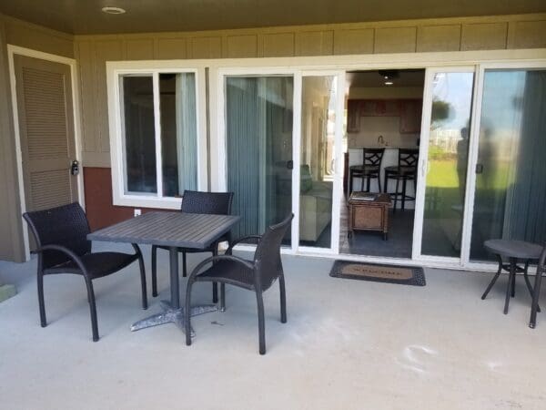 A patio with table and chairs outside of sliding glass doors.