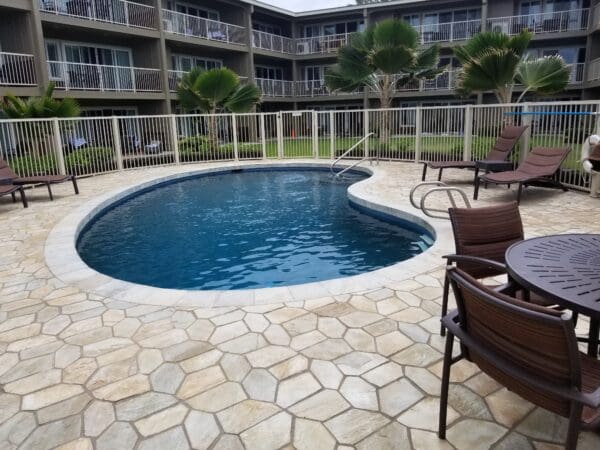 A pool with chairs and tables around it