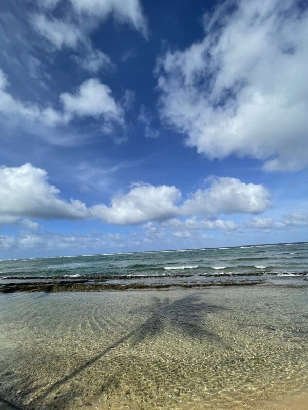 A beach with waves and clouds in the sky.