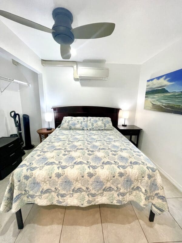 A bedroom with a bed, two nightstands and a fan.