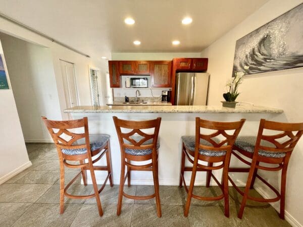 A kitchen with wooden chairs and white counter tops.