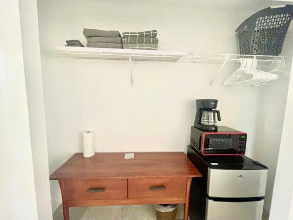 A small kitchen with a microwave, coffee pot and refrigerator.