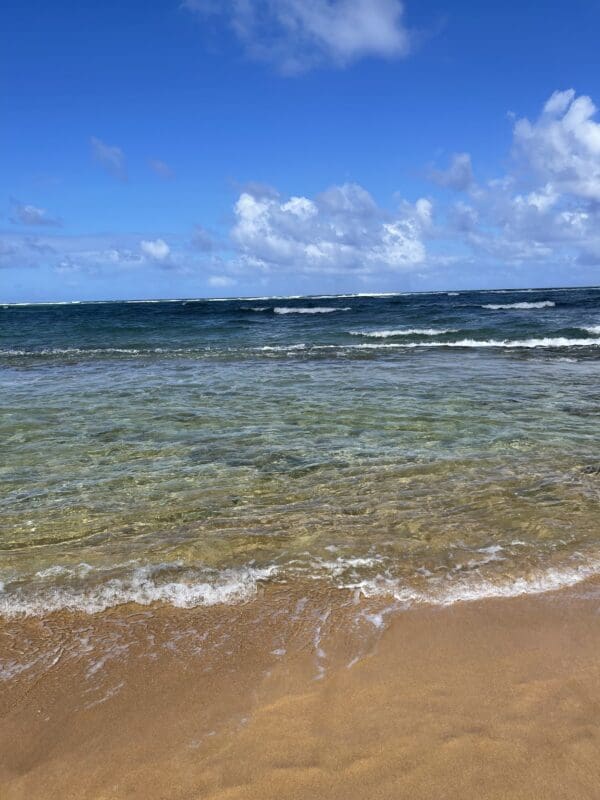 A beach with waves coming in from the ocean.