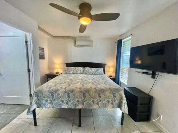 A bedroom with a bed, tv and dresser.