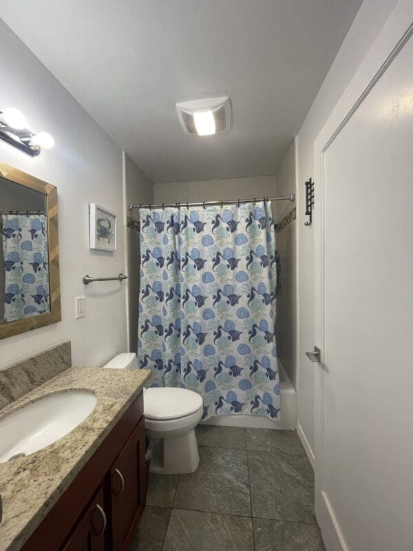 A bathroom with a toilet, sink and shower.