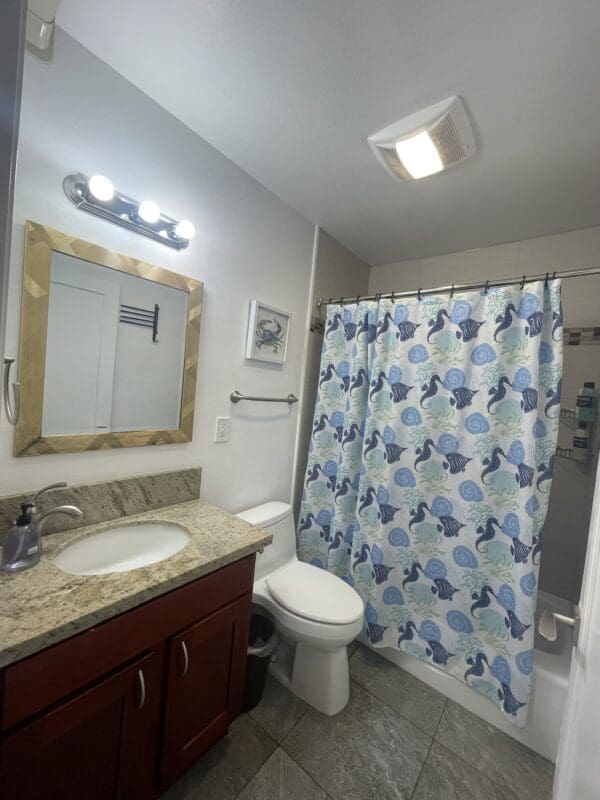 A bathroom with a toilet, sink and mirror.