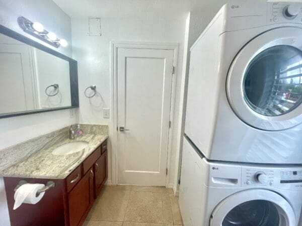 A bathroom with a sink and washer dryer.