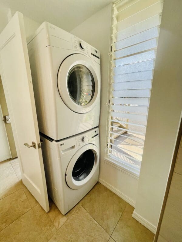 A white washer and dryer in the corner of a room.