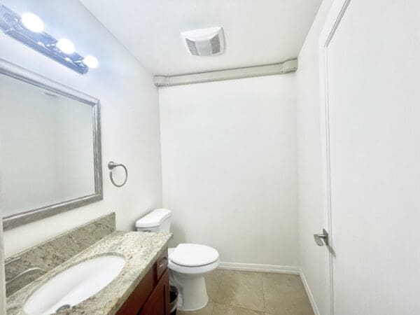 A bathroom with white walls and beige tile floors.