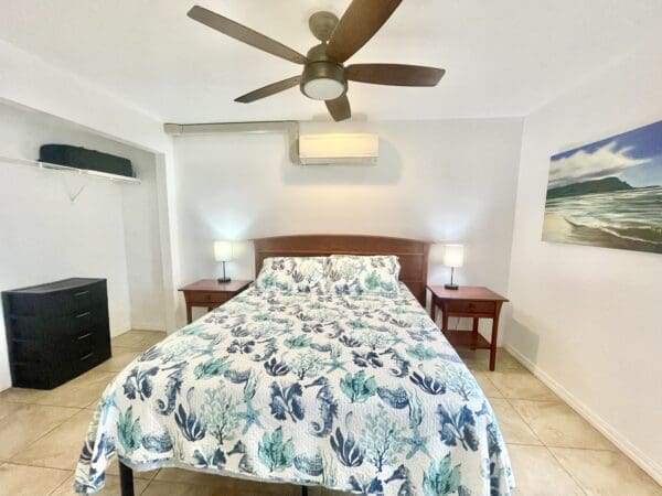 A bedroom with a bed, two night stands and a ceiling fan.