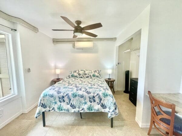 A bedroom with a bed, chair and table.