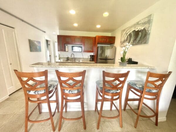 A kitchen with wooden chairs and marble counter tops.