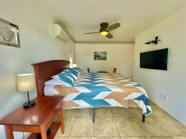 A bedroom with a bed, tv and table in it.