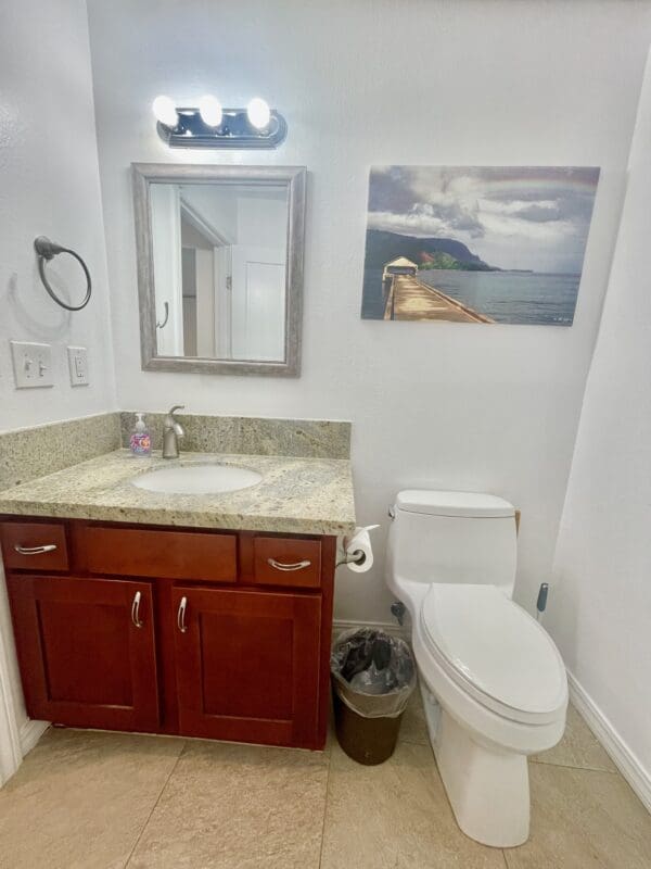 A bathroom with a sink, toilet and mirror.