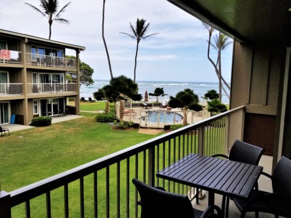 A balcony with chairs and tables overlooking the ocean.