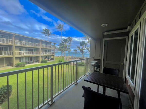 A balcony with chairs and tables overlooking the ocean.