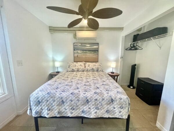 A bedroom with a bed, tv and ceiling fan.