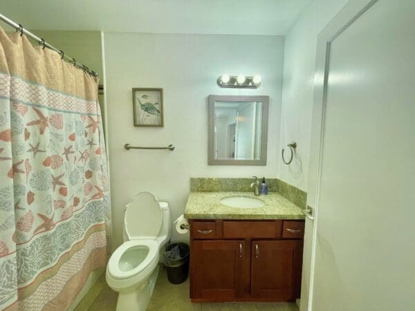 A bathroom with a toilet, sink and mirror.