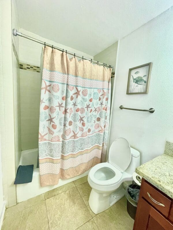 A bathroom with a toilet, sink and shower.