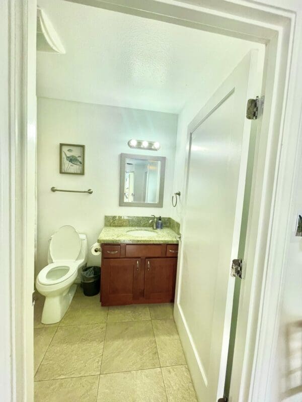 A bathroom with a toilet, sink and mirror.