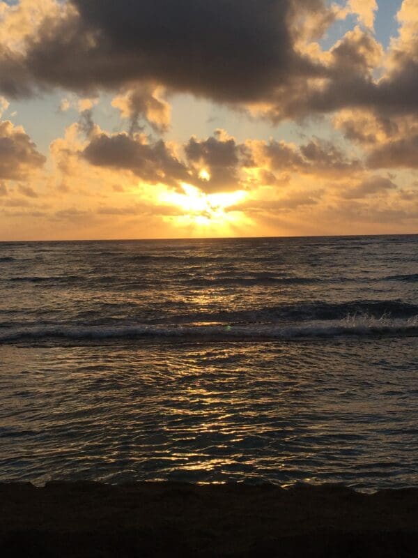 A sunset over the ocean with clouds in the sky.