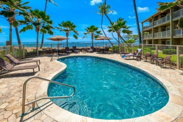 A pool with chairs and umbrellas in the background.