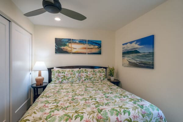 A bedroom with a bed, nightstand and two paintings.