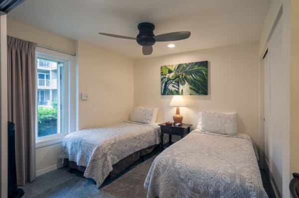 A bedroom with two beds and a ceiling fan.