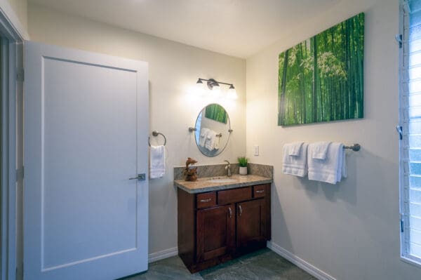 A bathroom with a sink, mirror and towel rack.