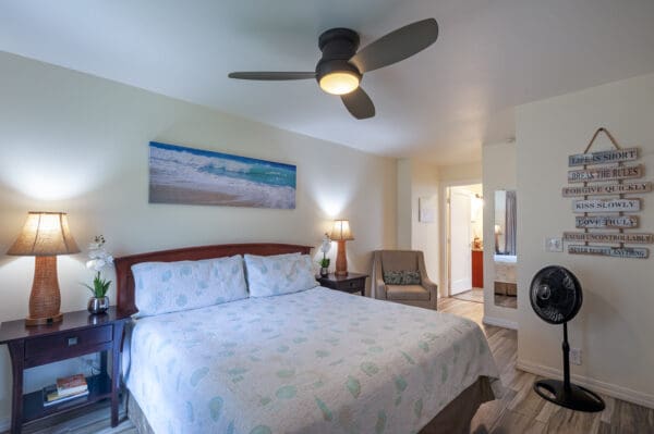 A bedroom with a bed, chair and fan.